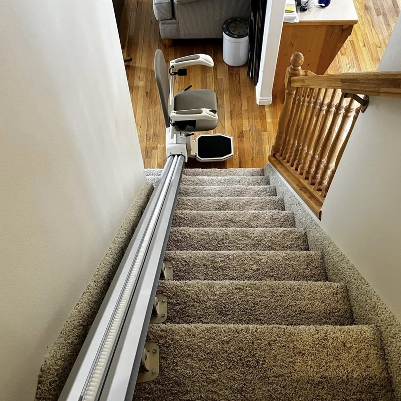 Stair lift rail running the length of a carpeted staircase