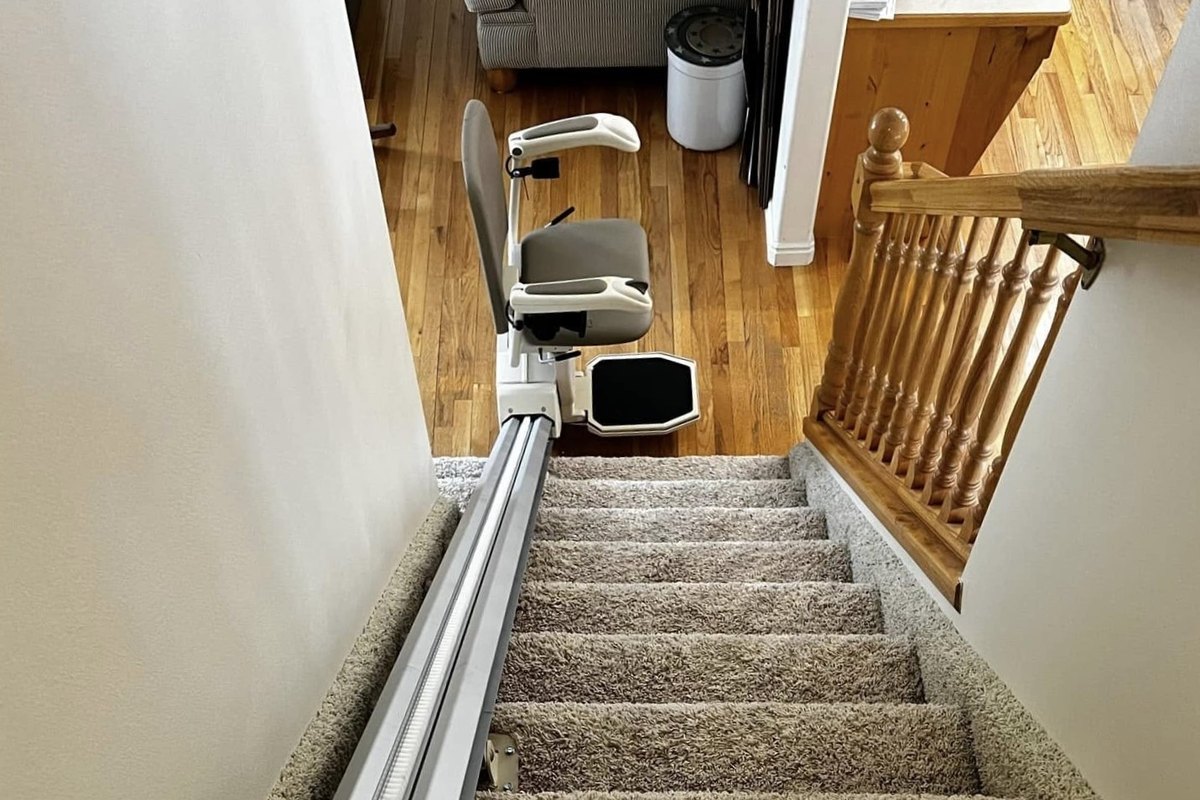 Long carpeted staircase with a stair lift rail running down to the bottom step