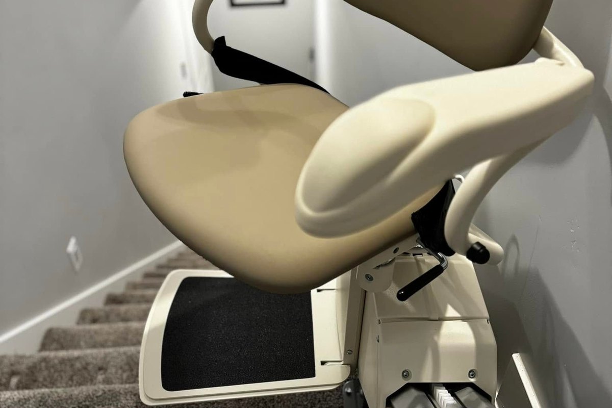 Seat and footrest of a Harmar SL600 stair lift at the top of a gray stairwell