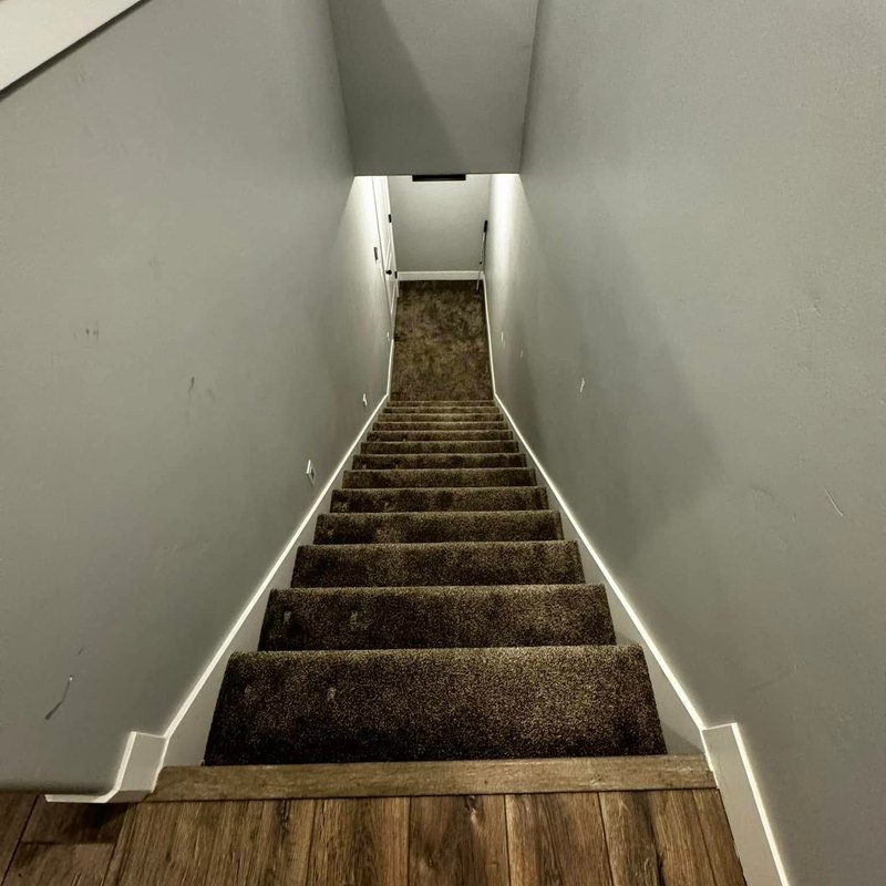 Long narrow carpeted staircase between light gray walls