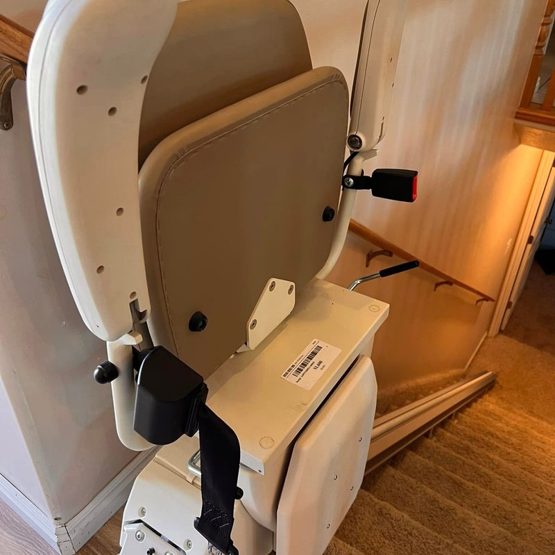 Harmar stair lift folded up at the bottom of a carpeted staircase