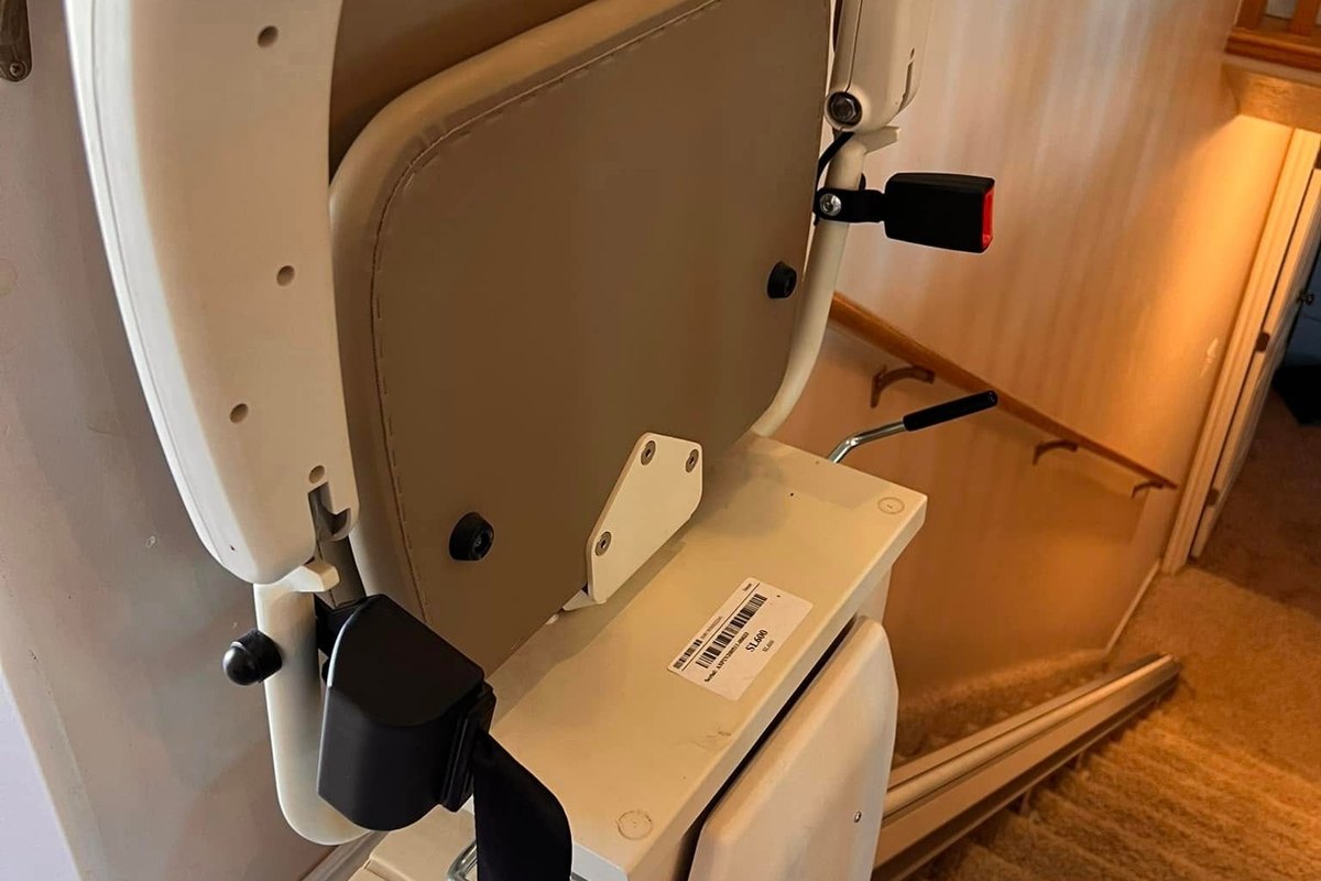 Harmar stair lift folded up at the foot of a carpeted staircase