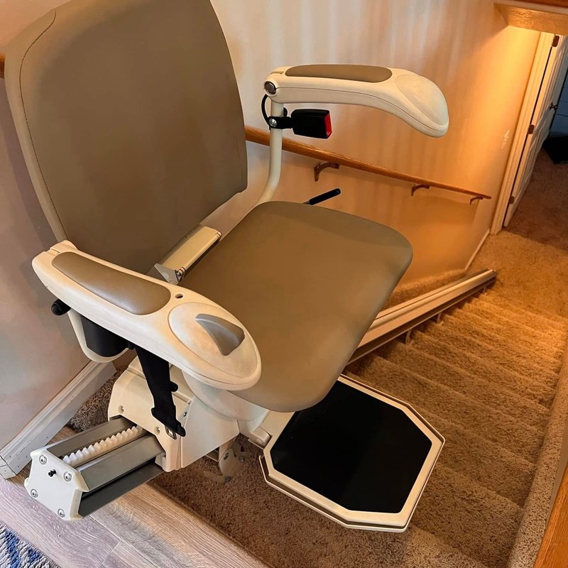 Harmar stair lift with the seat down at the bottom of a carpeted staircase