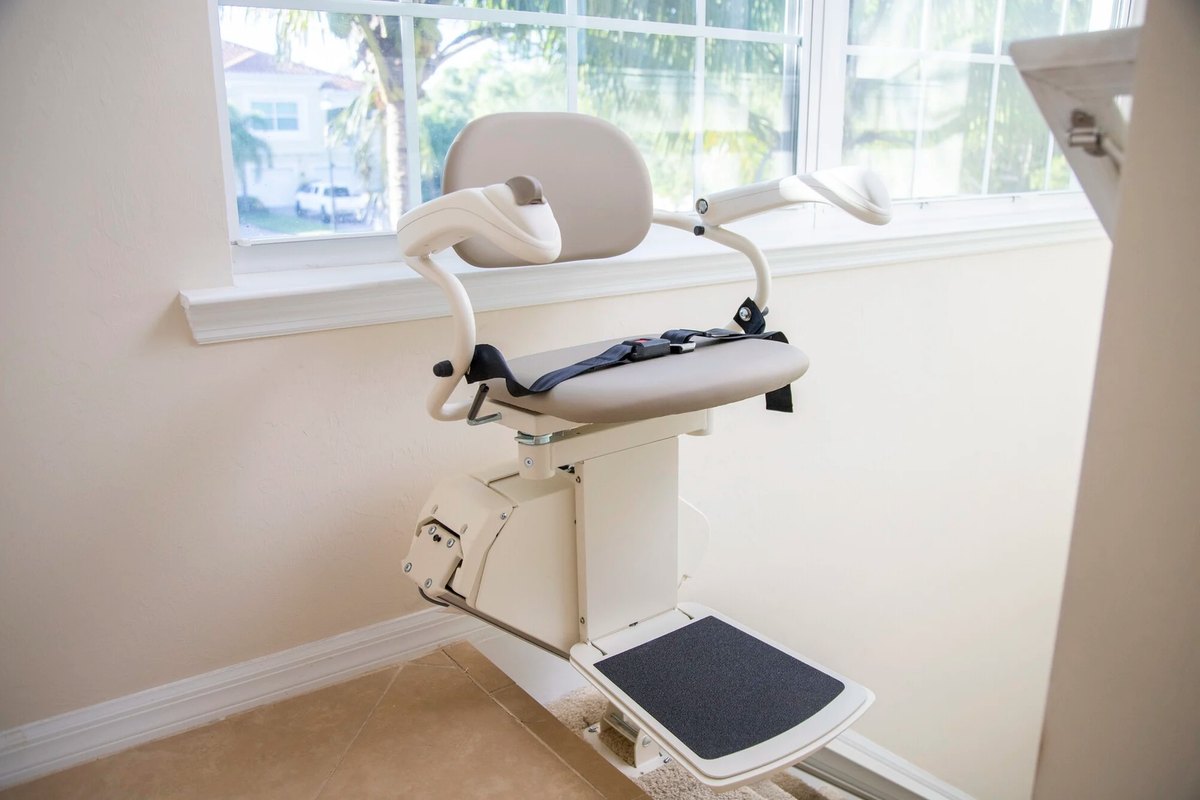 Harmar SL300 stair lift with its seat belt, parked at the top of a staircase beside a window