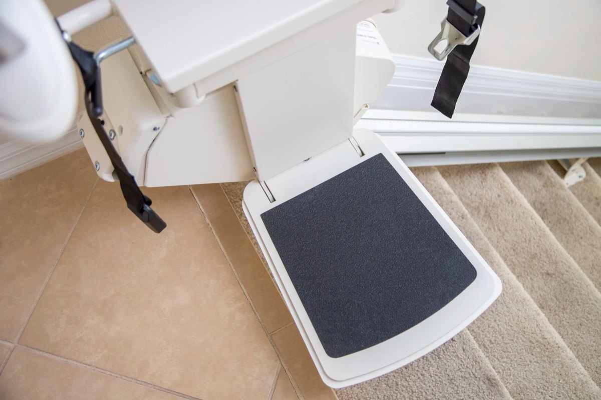 Lowered footrest of a Harmar SL300 stair lift at the top of a carpeted staircase