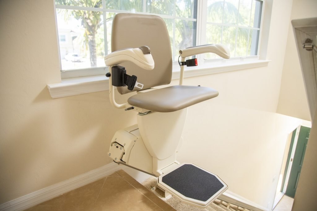 Harmar SL600 stair lift with its seat belt unbuckled, parked at the top of a staircase